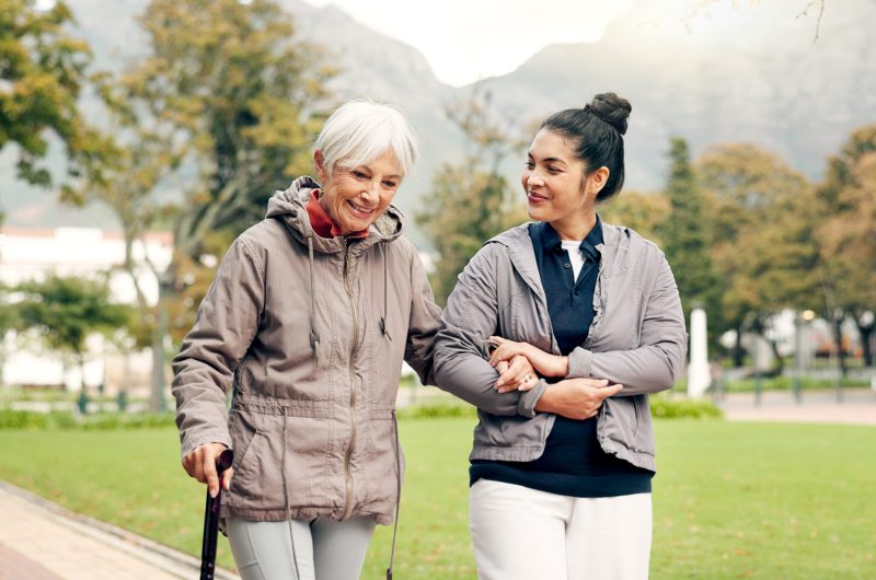 Senior woman, walker and nurse outdoor in a park with healthcare for elderly exercise. Walking, healthcare professional and female person with peace and physical therapy in a public garden with carer